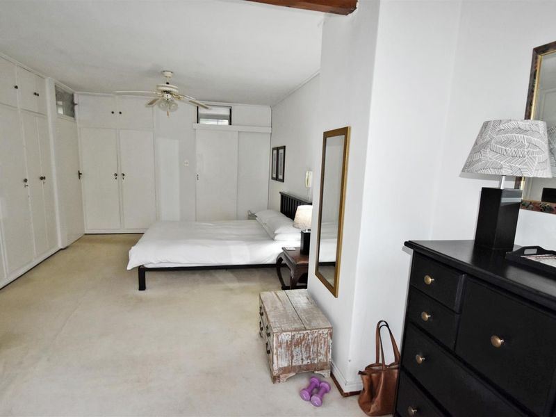 Spacious bedroom featuring extensive built-in cupboard storage and a ceiling fan, offering a neutral canvas for personalization.