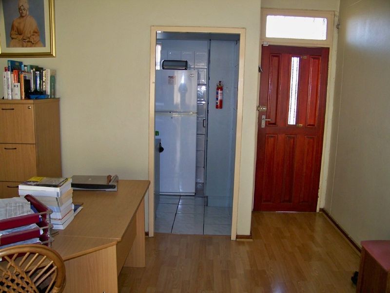 Entryway featuring laminate flooring and a solid timber front door, providing direct access to an adjacent kitchen area.