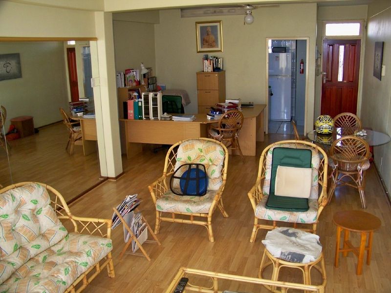 Open plan living area featuring laminate flooring and a ceiling fan, with direct access to an adjacent kitchen and secondary room.