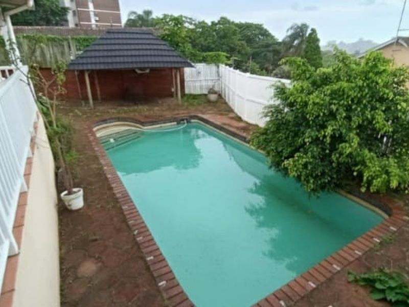 Outdoor pool area featuring a swimming pool, surrounding brick coping, and a small gazebo structure in the rear garden.