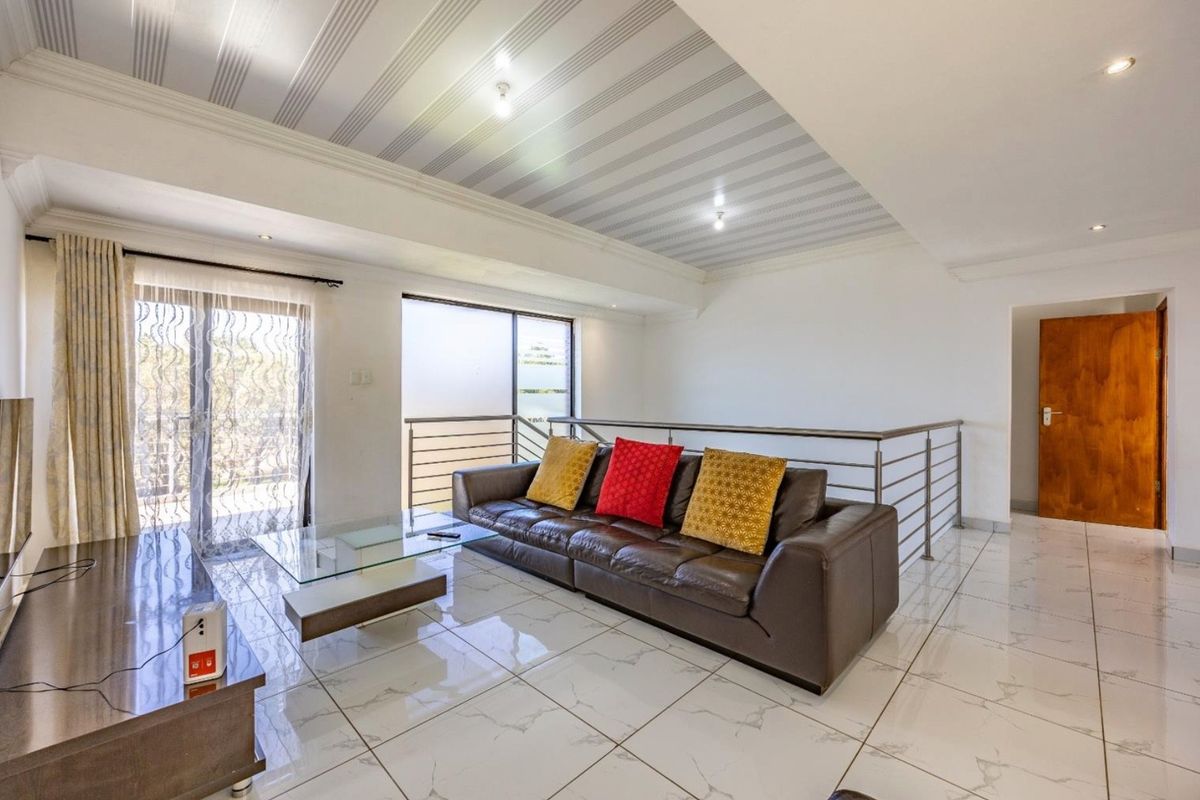 Spacious living area featuring polished marble-look floor tiles, a modern stainless steel balustrade, and large sliding doors providing natural light.