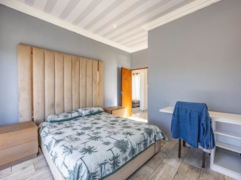 A well-maintained bedroom featuring a large built-in headboard, crown molding, recessed lighting, and a convenient built-in desk area with tiled flooring.