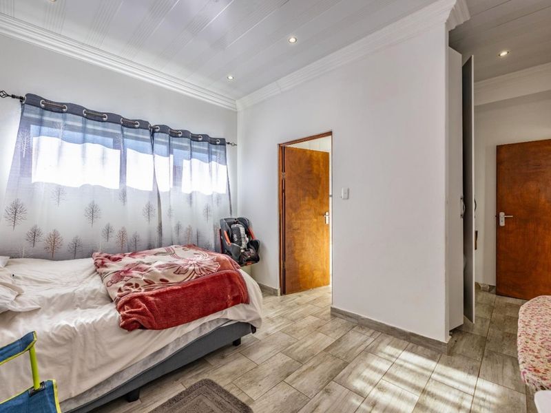 A well-lit bedroom featuring tiled flooring, crown molding, recessed ceiling lights, and built-in storage cupboards.