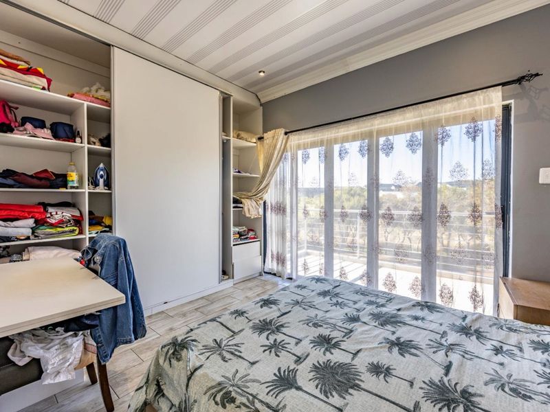 A well-lit bedroom featuring built-in wardrobe storage, tiled flooring, and large sliding glass doors providing access to an outdoor balcony area.