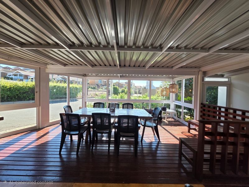 A covered patio area featuring timber decking, a corrugated metal roof, and extensive aluminum-framed windows providing natural light and garden views.