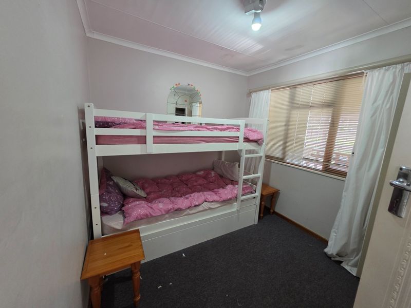 A compact bedroom featuring carpet flooring, venetian blinds, and cove cornicing, showing signs of ceiling water damage.