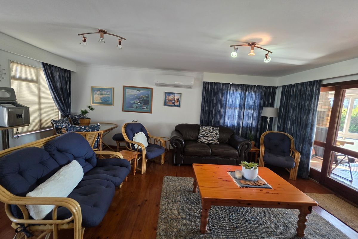 A spacious living room featuring polished hardwood flooring, split-system air conditioning, and direct access to an outdoor patio area through sliding glass doors.