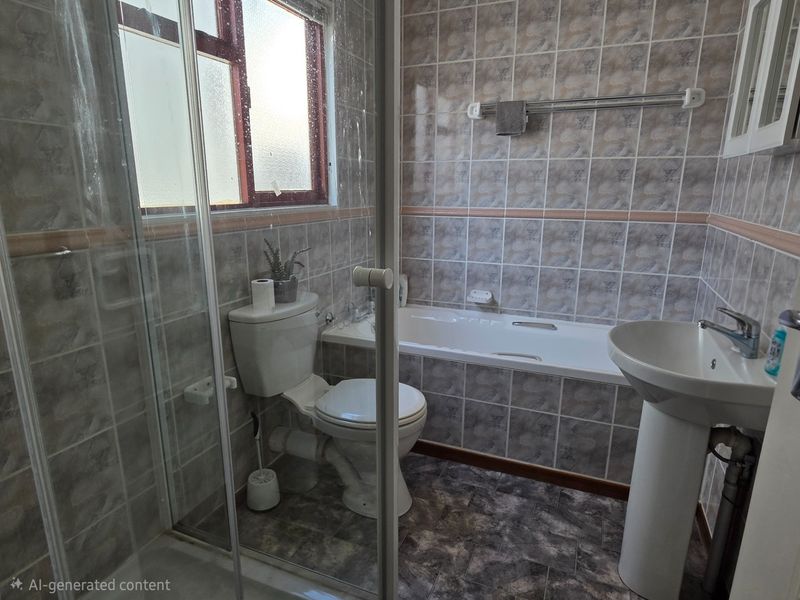 A functional bathroom featuring a pedestal basin, bathtub, and a separate shower enclosure with tiled finishes throughout.