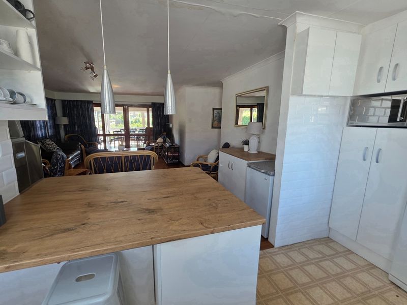 Open plan kitchen and living area featuring a breakfast island, built-in cabinetry, and direct access to the patio area.