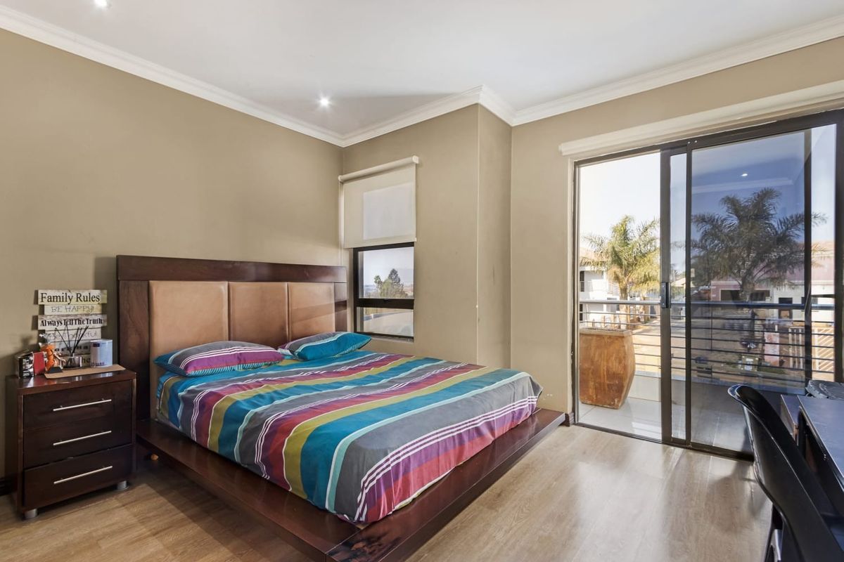 Spacious bedroom featuring laminate flooring, recessed lighting, and a sliding glass door providing direct access to a private balcony.