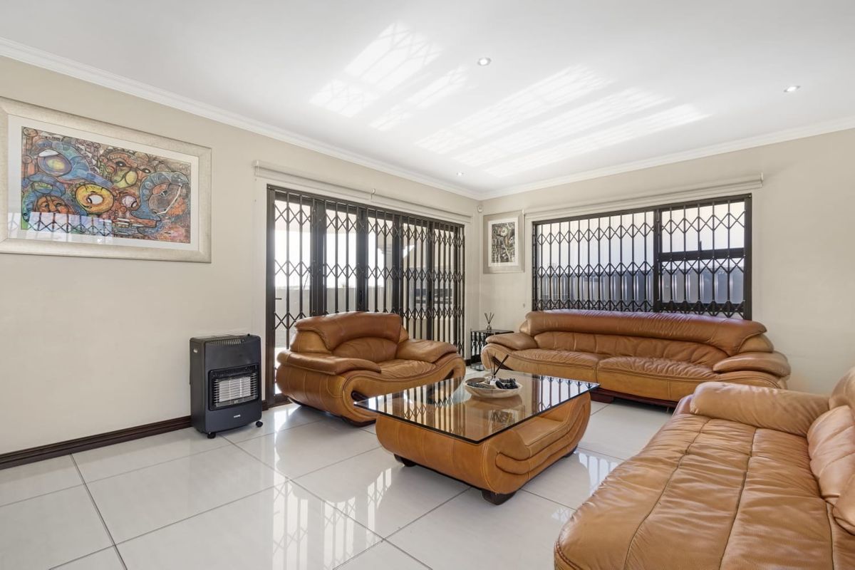 Spacious living room featuring polished tiled flooring, recessed downlighting, and secure sliding doors leading to the exterior.