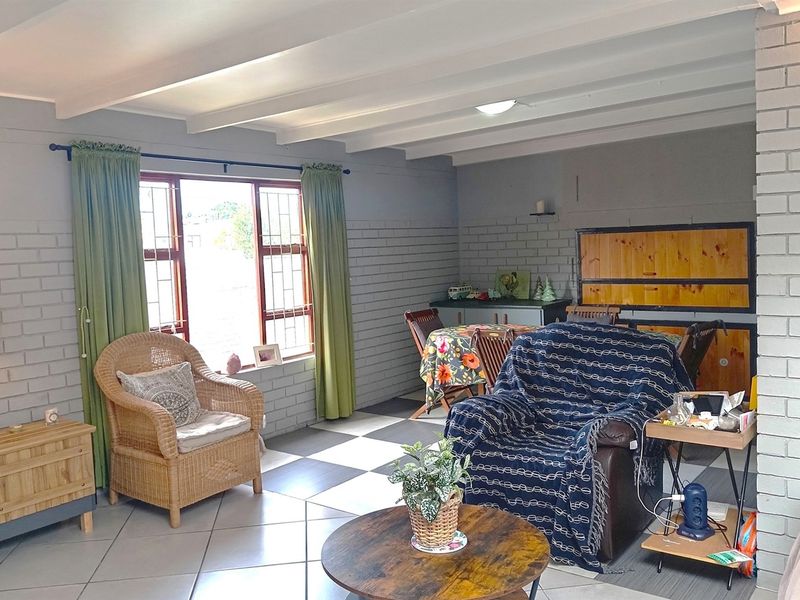 A living room featuring painted brick walls, exposed beam ceilings, and tiled flooring, offering a functional space with natural light.