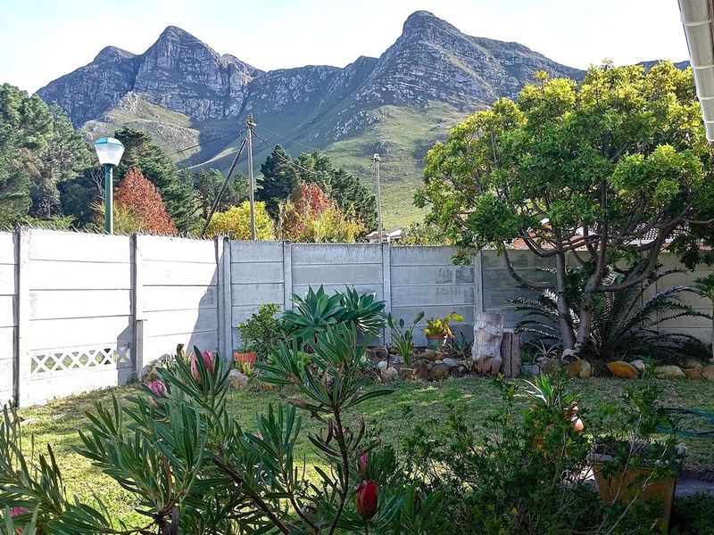 A private garden area featuring a precast concrete boundary wall and established landscaping, set against a scenic mountain backdrop.
