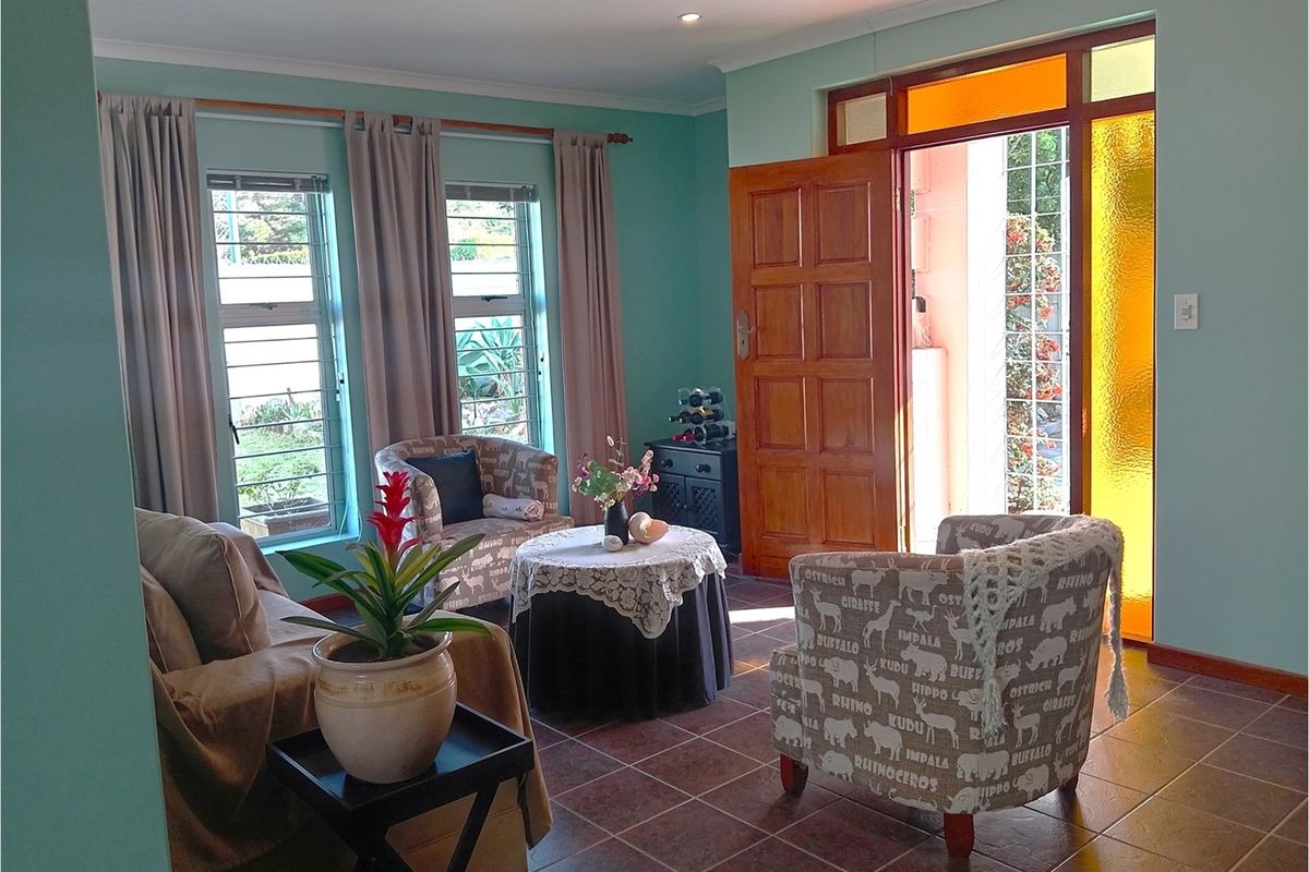 A bright living room featuring tiled flooring, recessed lighting, and direct access to the exterior through a timber door with decorative glass panels.