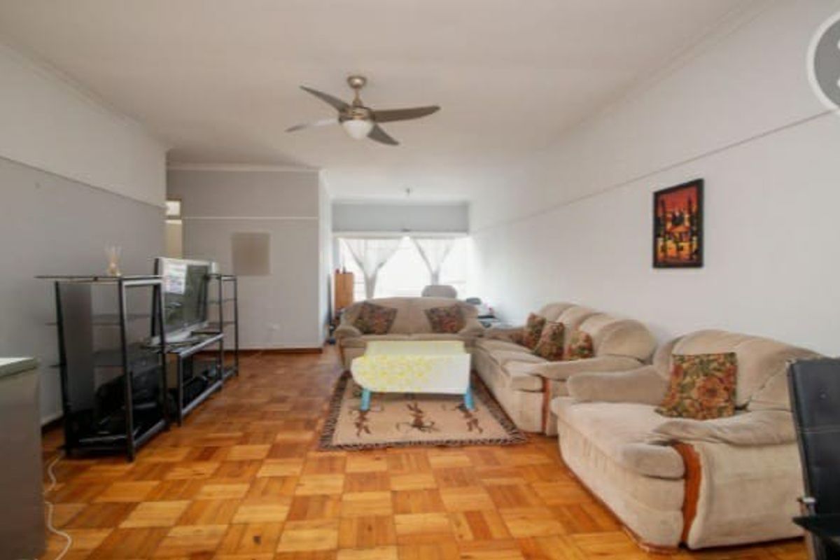 Spacious living room featuring classic parquet flooring, a ceiling fan, and traditional picture rails, offering a versatile layout for comfortable seating arrangements.