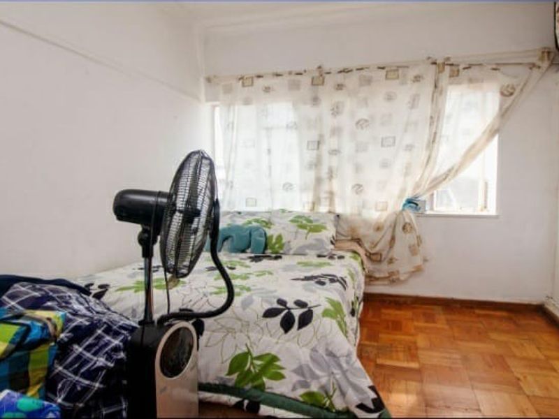 A compact bedroom featuring original parquet flooring and a built-in wardrobe, offering a functional space with potential for cosmetic updates.
