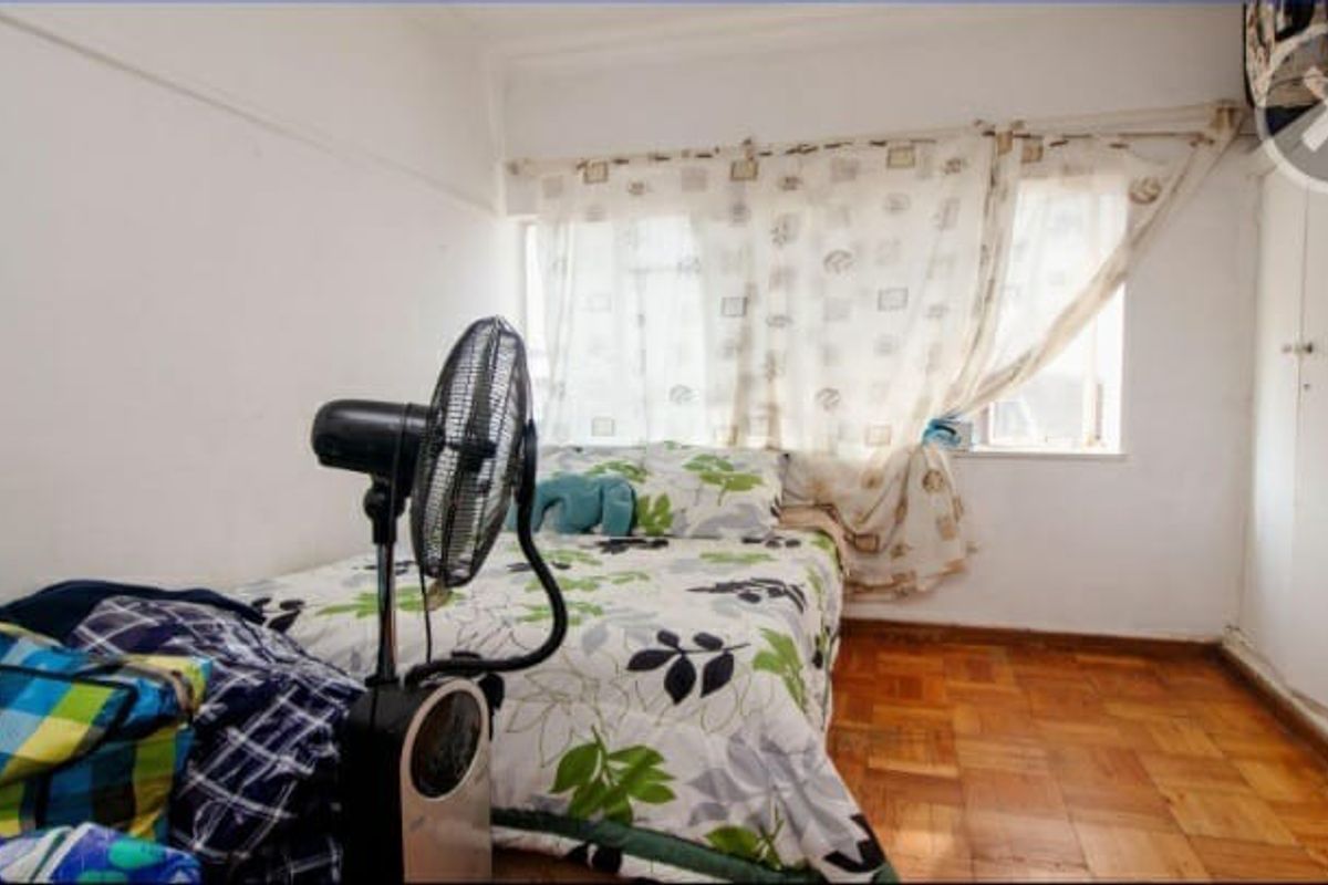 A compact bedroom featuring original parquet flooring and a built-in wardrobe, offering a functional space with potential for cosmetic updates.