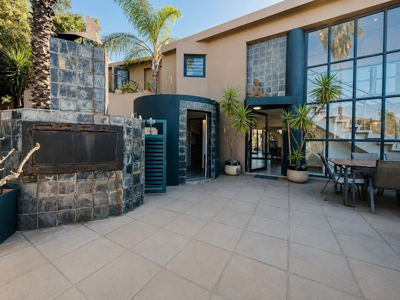 Spacious outdoor patio featuring a built-in tiled fireplace, large glass curtain wall, and direct access to the interior living space.