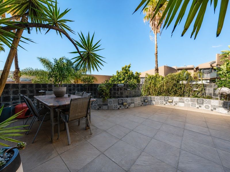 A spacious outdoor patio featuring tiled flooring and a decorative tiled retaining wall, perfect for alfresco dining and entertaining.