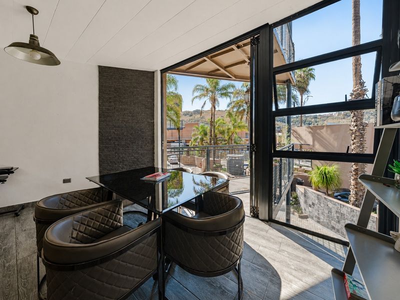 Modern open-plan living area featuring a striking stacked stone accent wall, large bi-fold doors opening to a balcony, and contemporary tiled flooring.