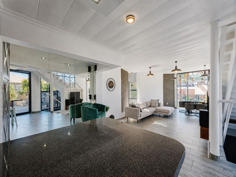 Spacious open-plan living area featuring tiled floors, a granite kitchen island, modern lighting, and large sliding doors leading to an outdoor patio.