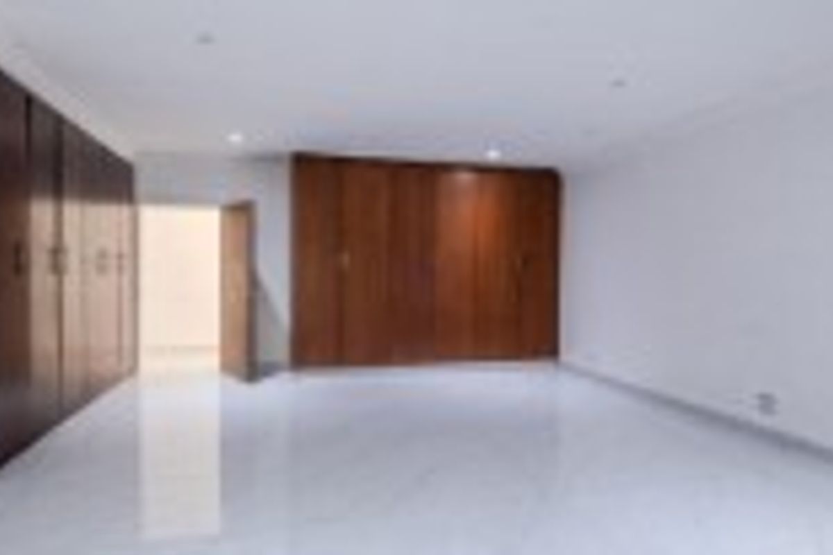 Spacious bedroom featuring extensive built-in wooden cabinetry, polished tiled flooring, and recessed ceiling lighting.