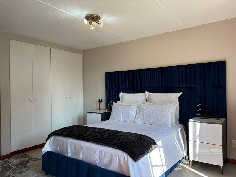 A well-maintained bedroom featuring built-in cupboards and a central ceiling light fixture.