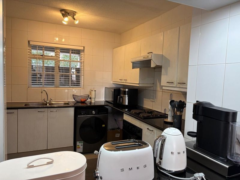 A functional kitchen featuring black granite countertops, white cabinetry, tiled splashbacks, and integrated cooking appliances, offering a clean and practical workspace.
