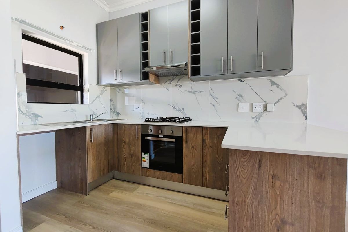 Modern kitchen featuring two-tone cabinetry, marble-look splashback, quartz countertops, and integrated appliances including a gas hob and oven.