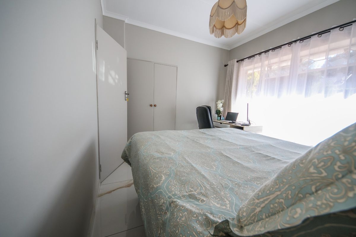 A well-maintained bedroom featuring neutral wall tones, tiled flooring, and built-in storage cupboards.