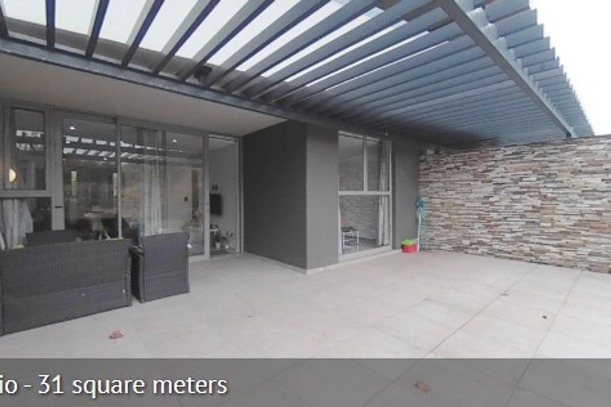 Spacious covered patio featuring a modern pergola, stone-clad feature wall, and large sliding glass doors providing seamless indoor-outdoor flow.
