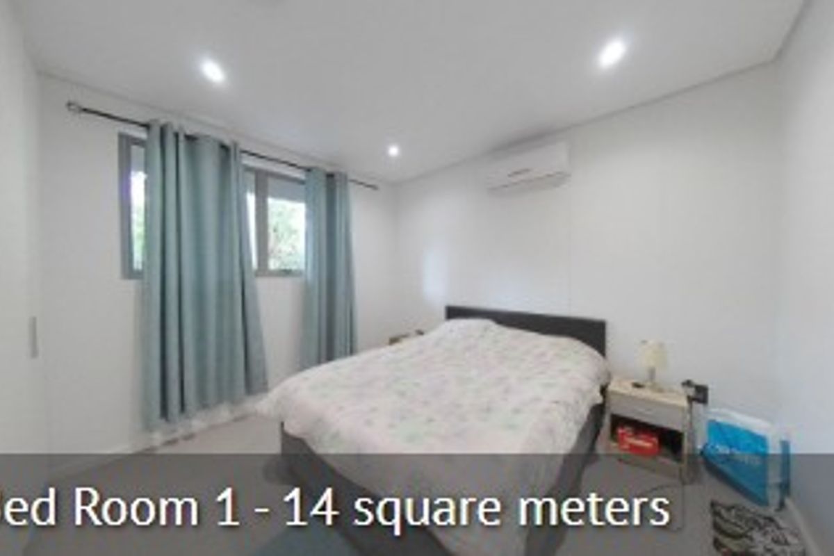 A bedroom featuring recessed downlighting and a wall-mounted split-system air conditioning unit.