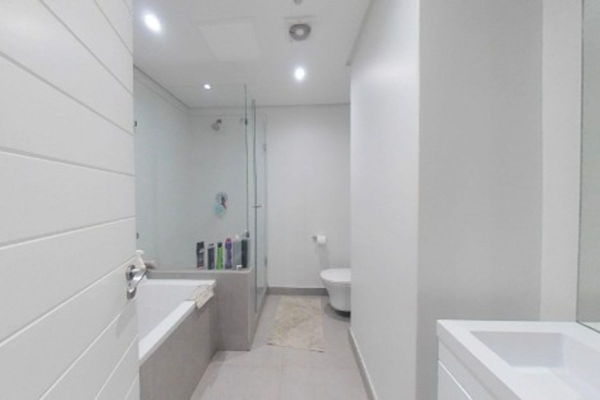 Modern bathroom featuring a built-in bathtub, separate glass-enclosed shower, wall-mounted toilet, and a sleek vanity basin with integrated storage.