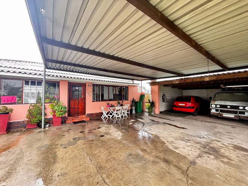 A covered outdoor patio and carport area featuring a corrugated metal roof, concrete flooring, and direct access to the main dwelling.