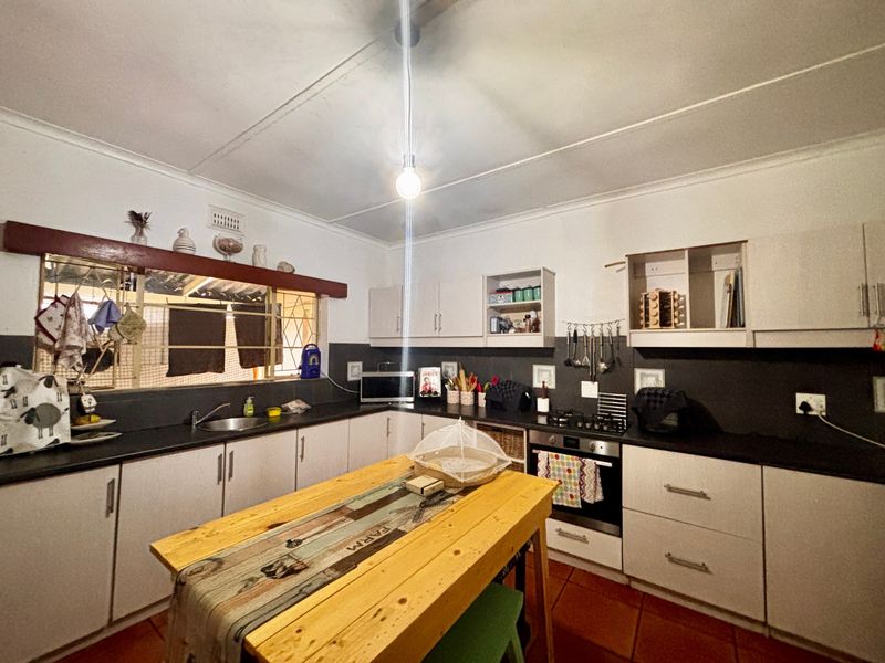 Functional kitchen featuring built-in cabinetry, dark countertops, integrated oven and hob, and tiled flooring with security bars on the window.