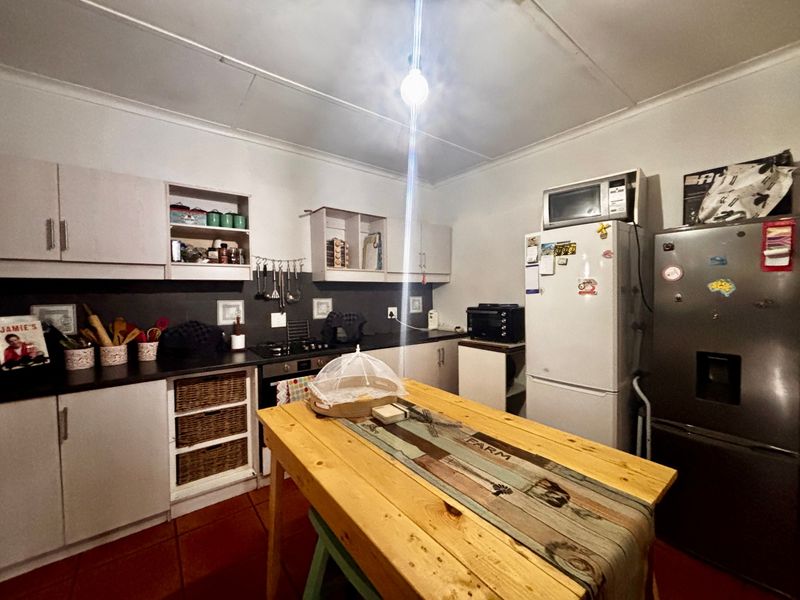 A functional kitchen featuring built-in cabinetry, laminate countertops, a built-in oven, and hob, finished with tiled flooring.