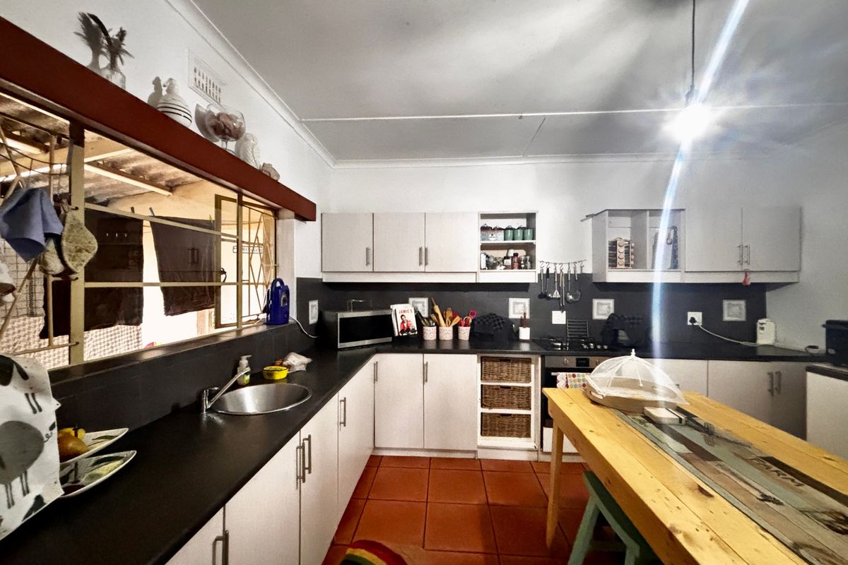 A functional kitchen featuring built-in cabinetry, dark countertops, a built-in oven, and tiled flooring, with an open-plan layout and direct access to an outdoor area.