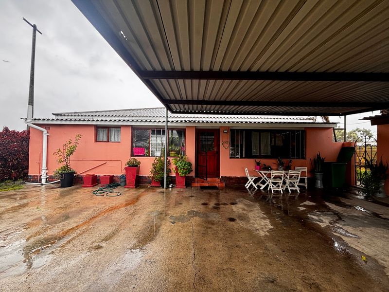 Rear exterior view of the farm property featuring a large corrugated metal carport and a concrete driveway area.