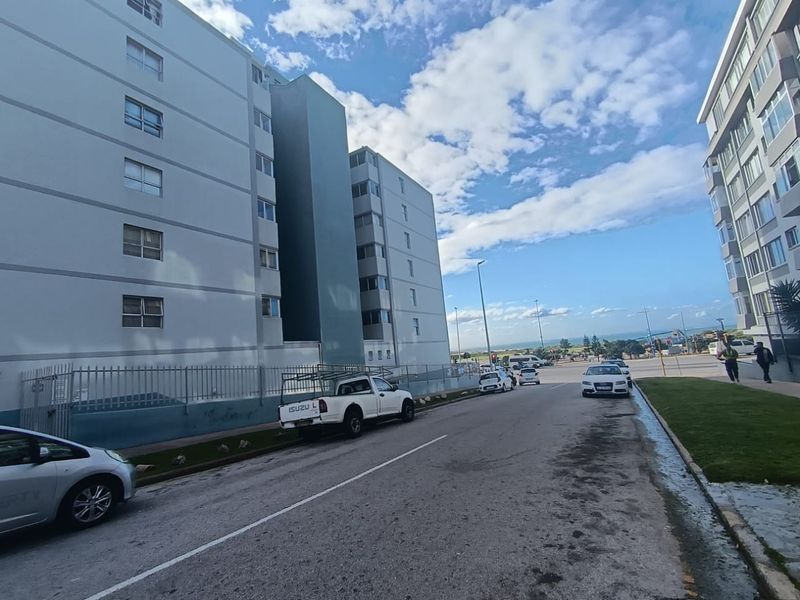 Street view showing the exterior facade of the apartment building, adjacent road, and surrounding neighborhood infrastructure.