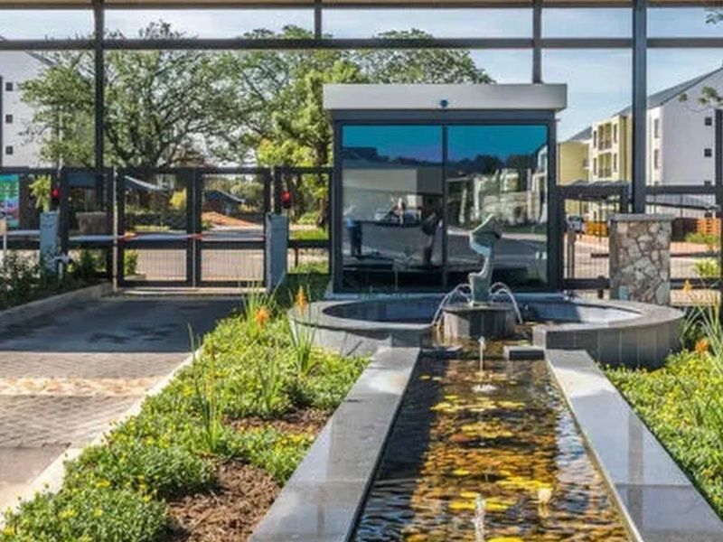 The secure entrance to Greenlee estate featuring a modern guard house, landscaped water feature, and controlled access gates.