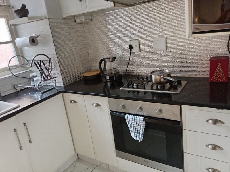 A functional kitchen featuring built-in cabinetry, granite countertops, a gas hob, an integrated oven, and a modern tiled backsplash.