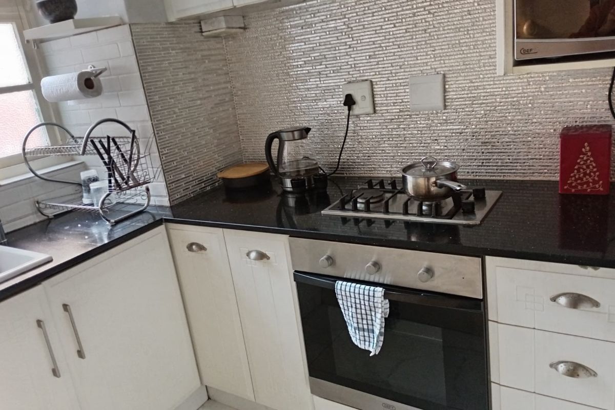 A functional kitchen featuring built-in cabinetry, granite countertops, a gas hob, an integrated oven, and a modern tiled backsplash.
