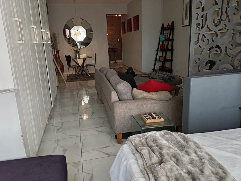An open-plan living area featuring polished marble-look floor tiles and built-in storage cupboards, creating a modern and cohesive living space.