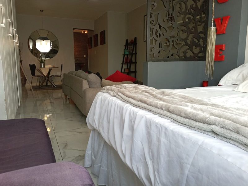 Open plan living area featuring polished tiled flooring, built-in storage cupboards, and a decorative partition wall separating the bedroom and living space.
