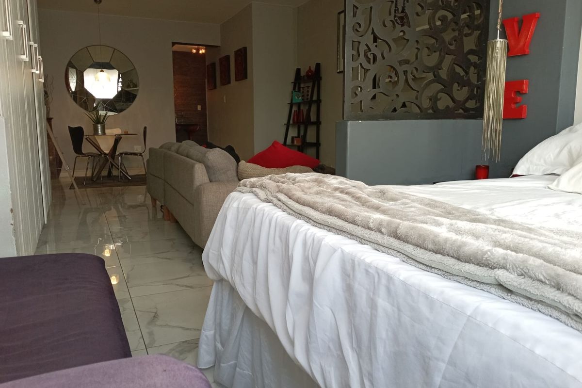 Open plan living area featuring polished tiled flooring, built-in storage cupboards, and a decorative partition wall separating the bedroom and living space.