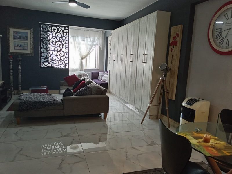 Spacious living area featuring large-format marble-look floor tiles, extensive built-in storage cabinetry, and a ceiling fan.