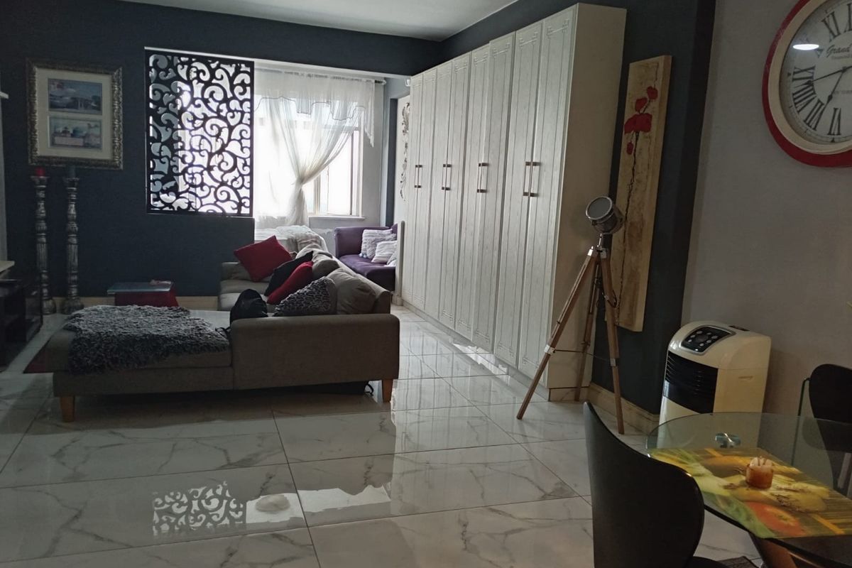 Spacious living area featuring large-format marble-look floor tiles, extensive built-in storage cabinetry, and a ceiling fan.