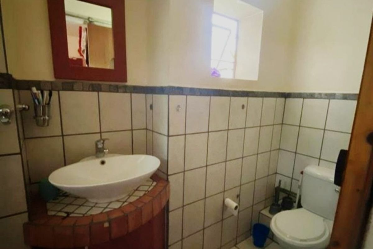 A compact bathroom featuring a vessel sink on a corner vanity cabinet, a standard toilet, and tiled wall and floor finishes.
