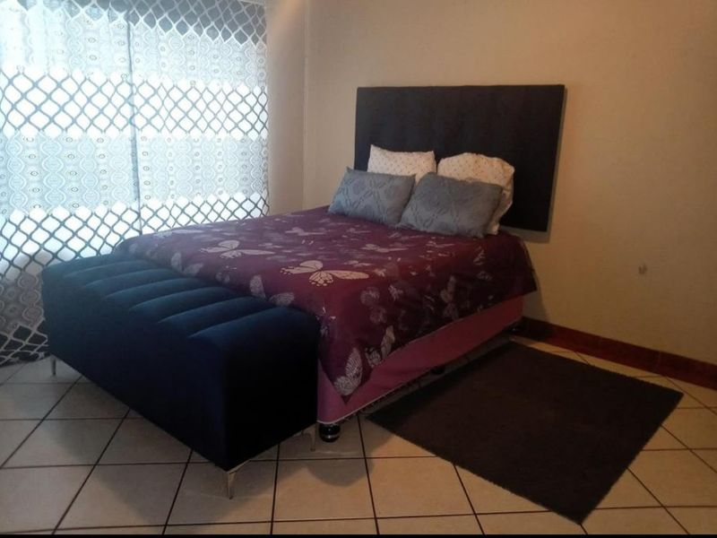 A bedroom featuring tiled flooring and a window with patterned curtains.