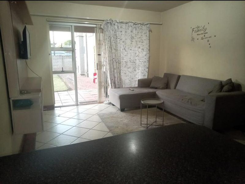 A living room featuring tiled flooring and a sliding glass door providing access to an outdoor patio area.